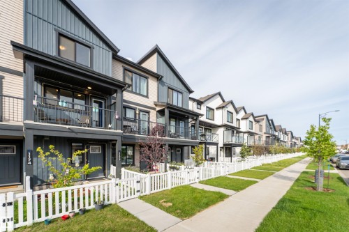 Modern townhome with a dark gray and beige vertical siding facade, featuring a private balcony with black railings - 1172 Aster Boulevard Nw Nw, Edmonton, AB - Outdoor With Balcony With Facade