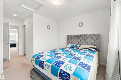 Carpeted room with a ceiling-mounted light fixture, white walls, and a window with sheer curtains - 1172 Aster Boulevard Nw Nw, Edmonton, AB - Indoor Photo Showing Bedroom