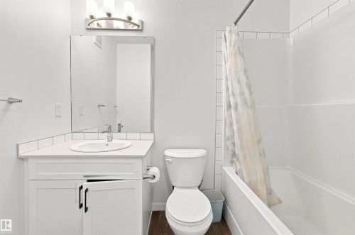 Modern bathroom with white vanity featuring dark hardware, a rectangular undermount sink, and a light-toned countertop - 1172 Aster Boulevard Nw Nw, Edmonton, AB - Indoor Photo Showing Bathroom