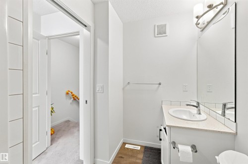 Bathroom vanity featuring a light-toned countertop, undermount sink, and chrome faucet - 1172 Aster Boulevard Nw Nw, Edmonton, AB - Indoor Photo Showing Bathroom