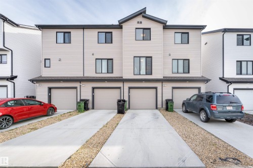 Three-story townhome featuring light-colored horizontal siding and dark trim accents - 1172 Aster Boulevard Nw Nw, Edmonton, AB - Outdoor With Facade