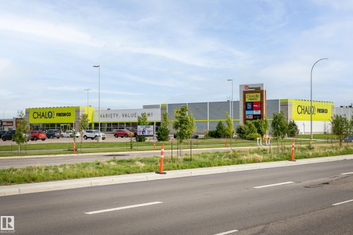 Modern commercial building with a prominent sign tower, featuring a large parking area and landscaped green spaces - 1172 Aster Boulevard Nw Nw, Edmonton, AB - Outdoor
