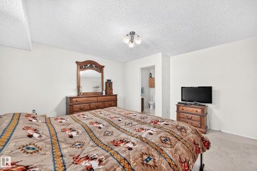 Carpeted flooring, neutral wall tones, and an attached three-light ceiling fixture - 2404 37 Street Nw, Edmonton, AB - Indoor Photo Showing Bedroom