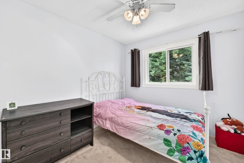 White walls, ceiling fan with integrated lighting, a window with exterior tree scenery, and light-toned carpeting - 2404 37 Street Nw, Edmonton, AB - Indoor Photo Showing Bedroom