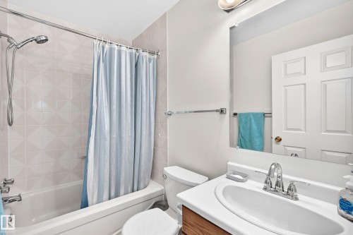 White rectangular bathtub with a chrome shower head and light-toned tile surround - 2404 37 Street Nw, Edmonton, AB - Indoor Photo Showing Bathroom
