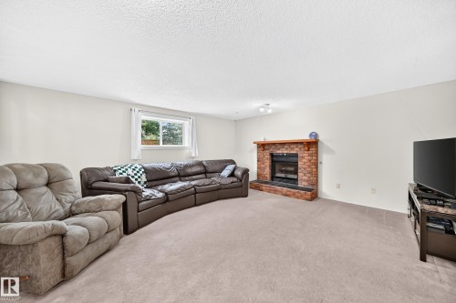 Spacious living area featuring a brick fireplace with a wood mantle, neutral carpeting, and recessed lighting - 2404 37 Street Nw, Edmonton, AB - Indoor Photo Showing Living Room With Fireplace