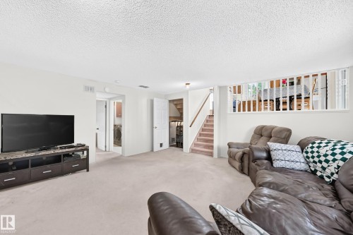 Carpeted flooring throughout, white wall finishes, and a staircase with wood-finish handrails - 2404 37 Street Nw, Edmonton, AB - Indoor Photo Showing Living Room
