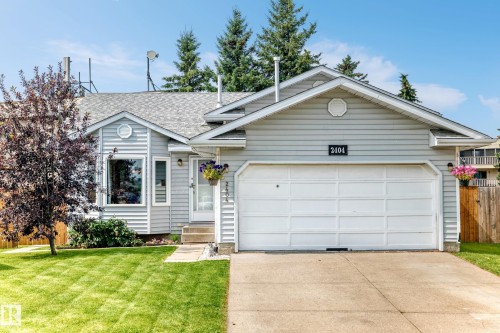 Light gray siding exterior with a concrete driveway, attached garage, and a manicured lawn - 2404 37 Street Nw, Edmonton, AB - Outdoor