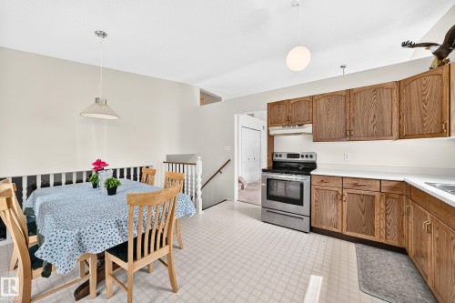 Spacious kitchen and dining area featuring wood-finish cabinetry, white countertops, stainless steel electric range, and light-toned flooring - 2404 37 Street Nw, Edmonton, AB - Indoor