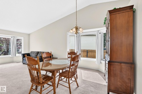 Vaulted ceiling, bay window, chandelier, carpet flooring, and neutral wall tones - 2404 37 Street Nw, Edmonton, AB - Indoor Photo Showing Dining Room