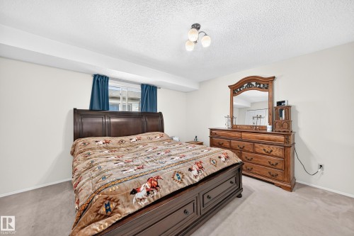 Wall-to-wall carpeting and a ceiling-mounted light fixture illuminate this room with neutral-toned walls - 2404 37 Street Nw, Edmonton, AB - Indoor Photo Showing Bedroom