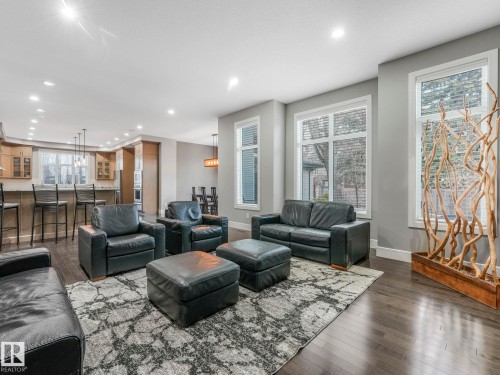 Hardwood-style flooring, recessed lighting, expansive windows, light gray wall paint, and a kitchen bar with pendant lighting - 8927 120 Street Nw, Edmonton, AB - Indoor Photo Showing Living Room