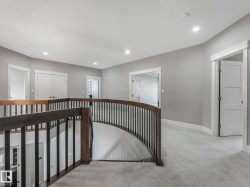 Curved staircase with wood-finish handrail and black balusters - 