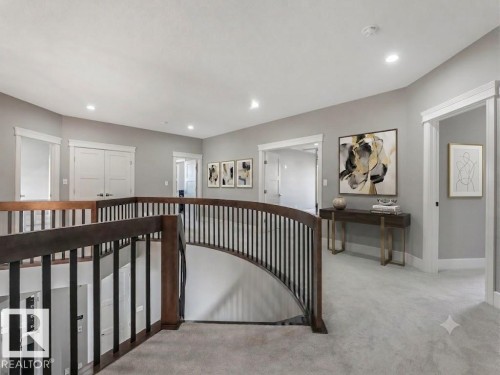 Curved wood and metal baluster railing, gray wall paint, light gray carpet, recessed ceiling lighting, and white trim - 8927 120 Street Nw, Edmonton, AB - Indoor Photo Showing Other Room