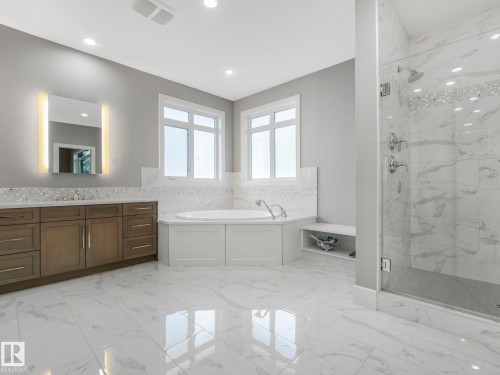 Polished tile flooring, dual-sink vanity with wood-finish cabinetry, built-in soaking tub, glass-enclosed shower, and recessed lighting - 8927 120 Street Nw, Edmonton, AB - Indoor Photo Showing Bathroom