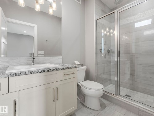 Modern vanity with a rectangular sink, granite-style countertop, and contemporary lighting - 8927 120 Street Nw, Edmonton, AB - Indoor Photo Showing Bathroom