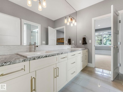 Dual vanity with integrated sinks, granite countertop, horizontal tile backsplash, and light wood-finish flooring - 8927 120 Street Nw, Edmonton, AB - Indoor Photo Showing Bathroom