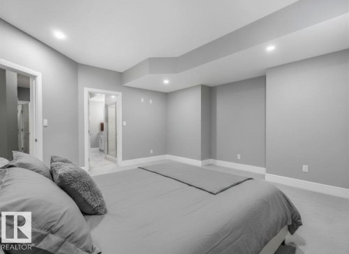 Recessed lighting, light gray wall paint, white trim, light-toned carpeting, and a doorway leading to a bathroom with a glass-enclosed shower - 8927 120 Street Nw, Edmonton, AB - Indoor