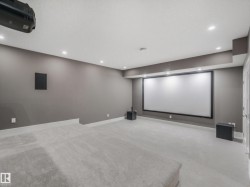 Dedicated media room with a large projection screen, recessed lighting, wall-mounted speakers, and plush carpet flooring - 