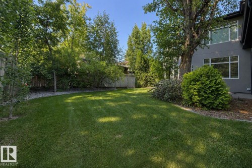 Expansive lawn bordered by mature trees and shrubs, featuring a gray exterior with multiple windows - 8927 120 Street Nw, Edmonton, AB - Outdoor