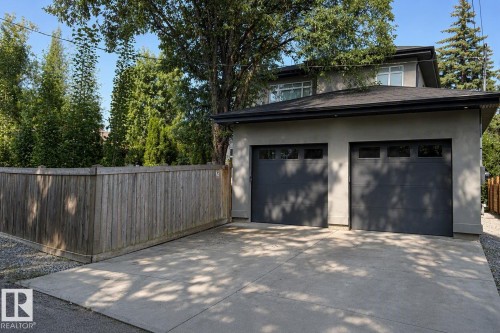 Two-car garage with contemporary doors, a concrete driveway, and stucco exterior - 8927 120 Street Nw, Edmonton, AB - Outdoor