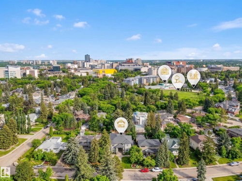 Aerial perspective highlighting the property within a residential district, featuring established green spaces and a distant city skyline - 8927 120 Street Nw, Edmonton, AB - Outdoor With View
