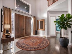 Two-story foyer featuring hardwood flooring, a high transom window, wood-paneled double entry doors, and an open staircase with wood railings - 