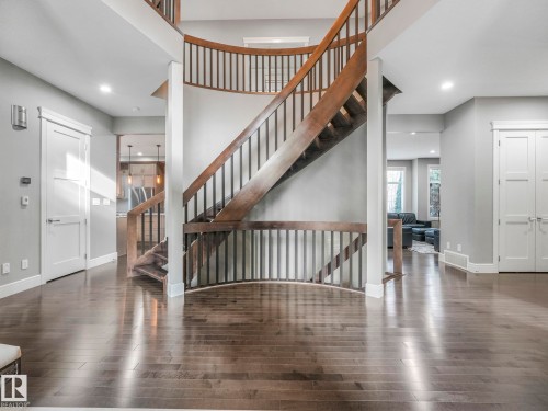 Curved staircase with wood-finish treads and metal balusters - 8927 120 Street Nw, Edmonton, AB - Indoor Photo Showing Other Room