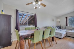 Dining area featuring light wood-finish flooring, a ceiling fan with light fixture, and a window providing natural light - 