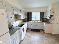 Kitchen featuring white cabinetry, green countertops, and a patterned tile backsplash - 