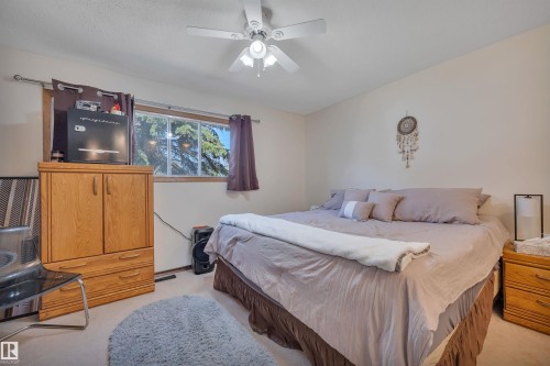 Bedroom featuring carpet flooring, a ceiling fan with integrated lighting, and a window with wood trim - 5411 44 Ave, Wetaskiwin, AB - Indoor Photo Showing Bedroom