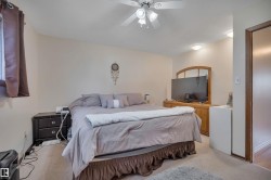 Carpeted room featuring a ceiling fan with integrated lighting, a window with curtains, and a wooden door frame - 