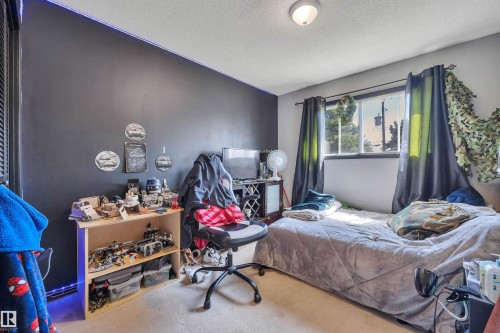 Carpeted room featuring a window with natural light, textured ceiling, and an overhead flush-mount light fixture - 5411 44 Ave, Wetaskiwin, AB - Indoor Photo Showing Bedroom