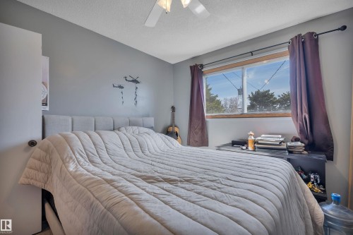 Bedroom featuring a window with wood trim, ceiling fan, and grey wall color - 5411 44 Ave, Wetaskiwin, AB - Indoor Photo Showing Bedroom