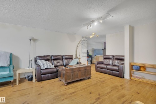 Spacious living area featuring wood-finish flooring, white walls, and track lighting - 5411 44 Ave, Wetaskiwin, AB - Indoor Photo Showing Living Room