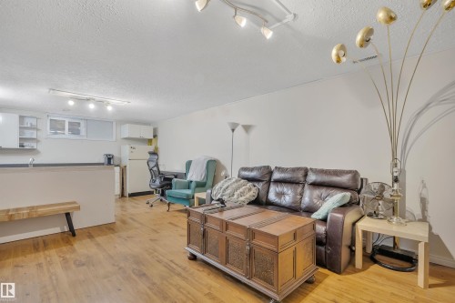 Open-concept living area featuring wood-finish flooring, white walls, and track lighting - 5411 44 Ave, Wetaskiwin, AB - Indoor
