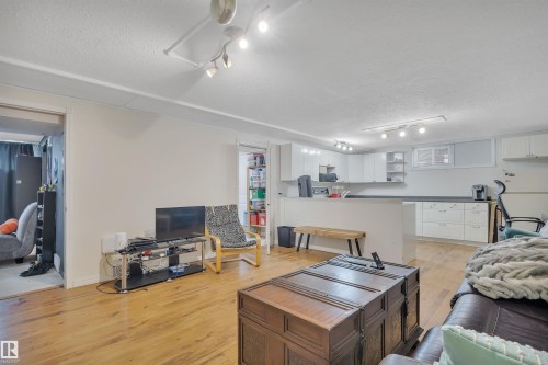 Open concept living area featuring wood-finish flooring, recessed lighting, and a kitchen with white cabinetry and dark countertops - 5411 44 Ave, Wetaskiwin, AB - Indoor