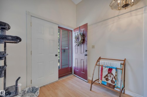Entryway featuring light wood-finish flooring, a red front door with a glass screen door, and a white six-panel interior door - 5411 44 Ave, Wetaskiwin, AB - Indoor Photo Showing Other Room