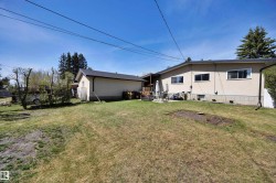 Expansive rear yard featuring a detached auxiliary building, concrete patio, and mature perimeter trees - 