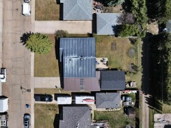 Property featuring a central residence with a metal roof and an attached auxiliary structure with an asphalt shingle roof - 