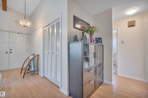 Entryway featuring wood-finish flooring, a bi-fold louvered closet, and an angled ceiling with a suspended light fixture - 5411 44 Ave, Wetaskiwin, AB - Indoor Photo Showing Other Room