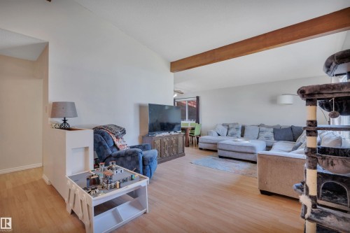 Spacious living area featuring wood-finish flooring, a prominent exposed wood beam, and recessed lighting - 5411 44 Ave, Wetaskiwin, AB - Indoor