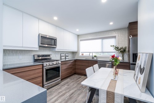Modern kitchen featuring two-tone cabinetry, stainless steel appliances, and a tiled backsplash - 10934 80 Avenue Nw, Edmonton, AB - Indoor