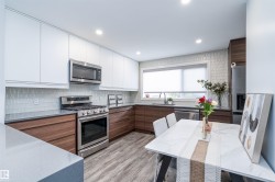Modern kitchen featuring two-tone cabinetry, stainless steel appliances, and a tiled backsplash - 