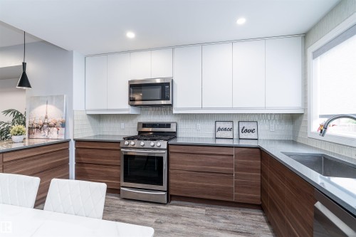 Modern kitchen featuring two-tone cabinetry, stainless steel appliances, and wood-finish flooring - 10934 80 Avenue Nw, Edmonton, AB - Indoor Photo Showing Kitchen