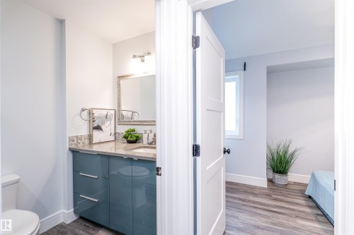 Bathroom featuring a blue vanity with a light-colored countertop, undermount sink, and tile backsplash - 10934 80 Avenue Nw, Edmonton, AB - Indoor Photo Showing Bathroom