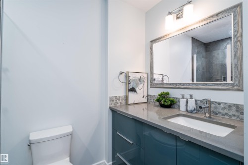 Modern bathroom featuring a single vanity with a sleek blue cabinet base, a light gray countertop, and an integrated white rectangular sink - 10934 80 Avenue Nw, Edmonton, AB - Indoor Photo Showing Bathroom