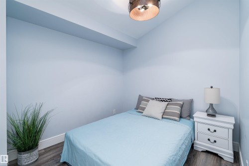 Light blue walls complement wood-finish flooring - 10934 80 Avenue Nw, Edmonton, AB - Indoor Photo Showing Bedroom