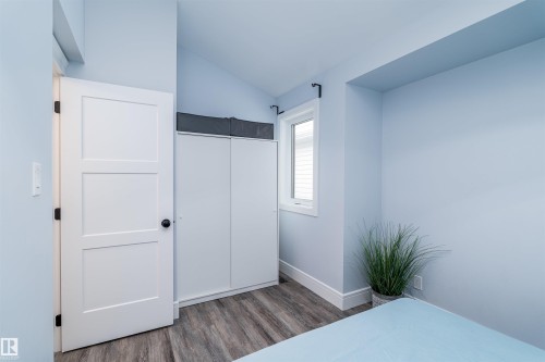 Interior room featuring wood-finish flooring, light blue wall paint, and white trim - 10934 80 Avenue Nw, Edmonton, AB - Indoor Photo Showing Bedroom