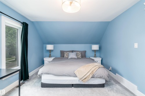 Attic space featuring sloped ceilings, a large window, light blue wall paint, wall-to-wall carpeting, and a flush mount ceiling light fixture - 10934 80 Avenue Nw, Edmonton, AB - Indoor Photo Showing Bedroom